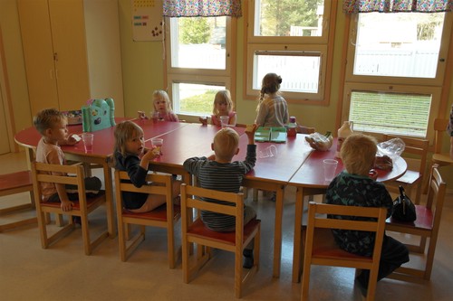 lapsia kerhossa pöydän ympärillä eväitä syömässä
